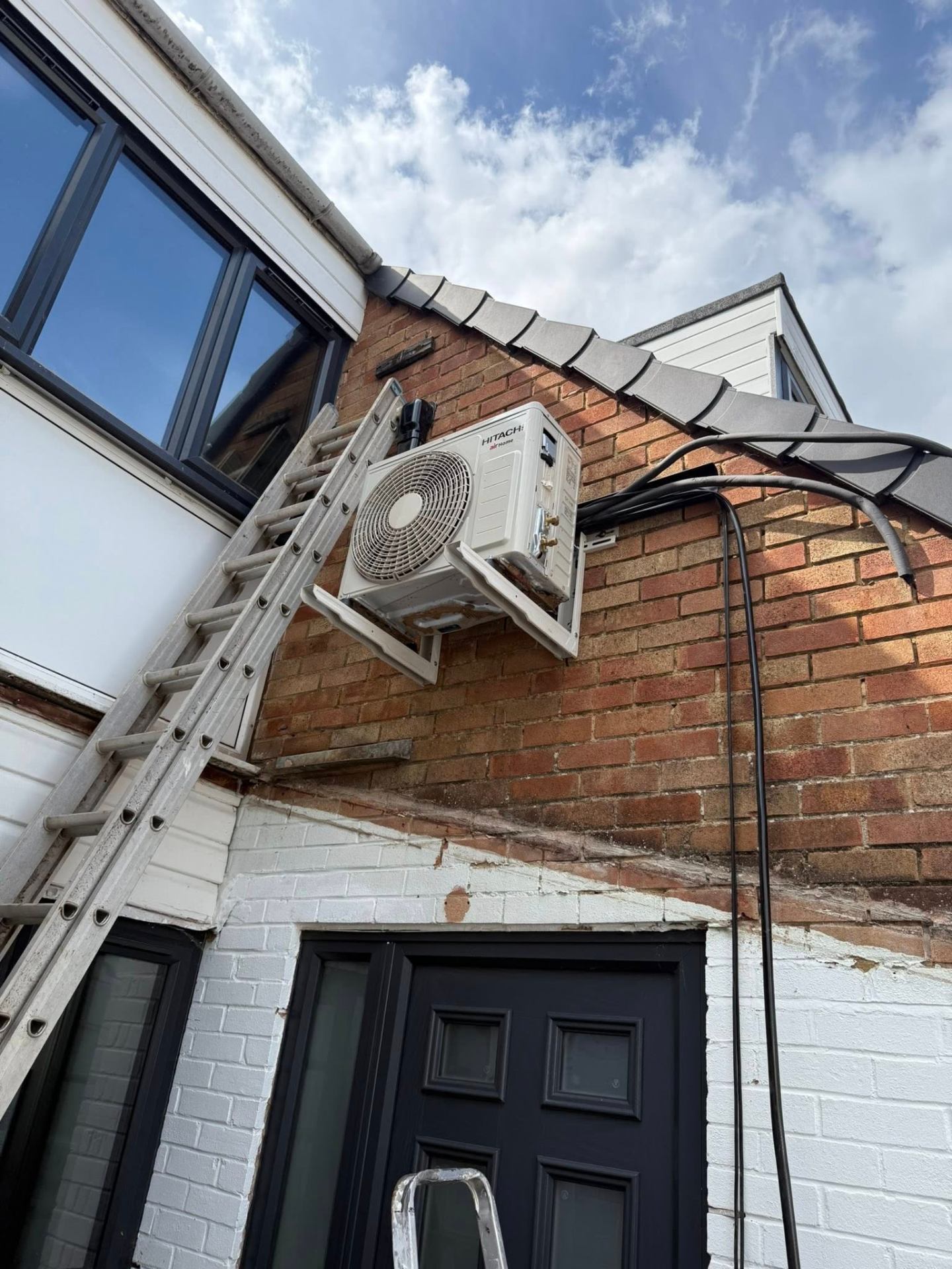 Hitachi air conditioning outdoor condenser unit wall-mounted on a Northampton property by J Lamb Plumbing & Heating